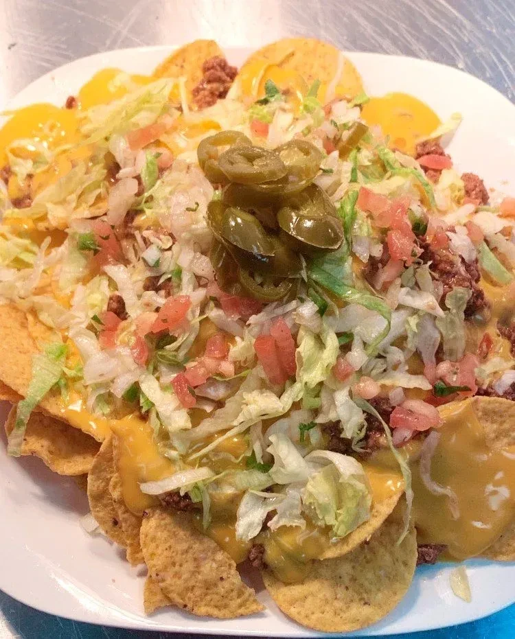 Fully loaded nachos with cheese, meat, lettuce, tomato, and jalapeños.