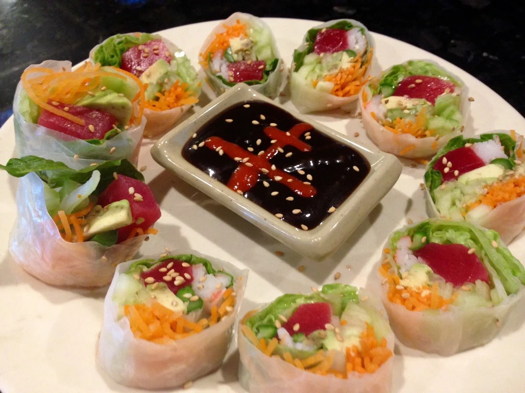 Fresh spring rolls with colorful fillings and garnished dipping sauce.
