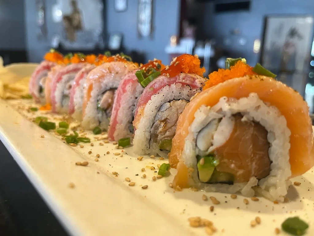 Platter of salmon and beef sushi rolls with tobiko and green onions.