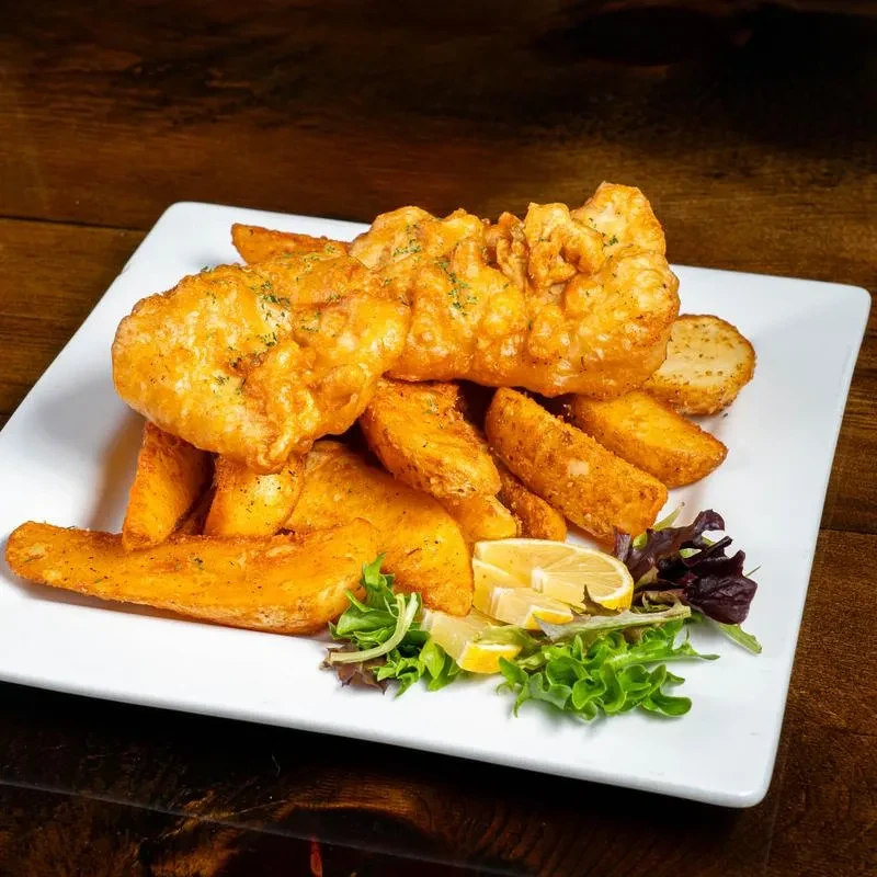 Classic fish and chips with herbs, lemon, and thick-cut wedges.