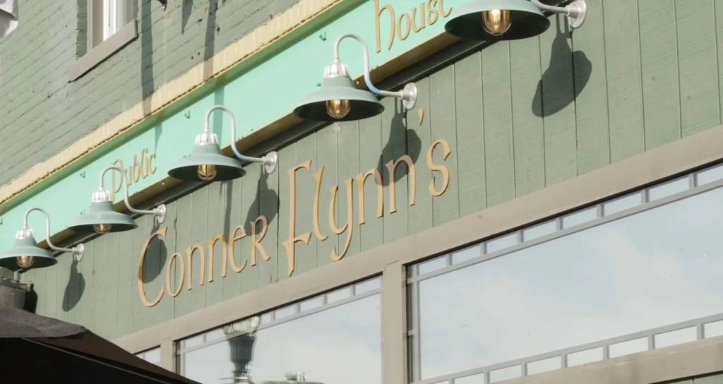 Green-paneled building facade with 'Conner Flynn's Public House' sign and lights.