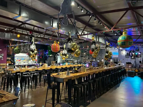 Empty industrial bar decorated festively with a stage and high-top tables.