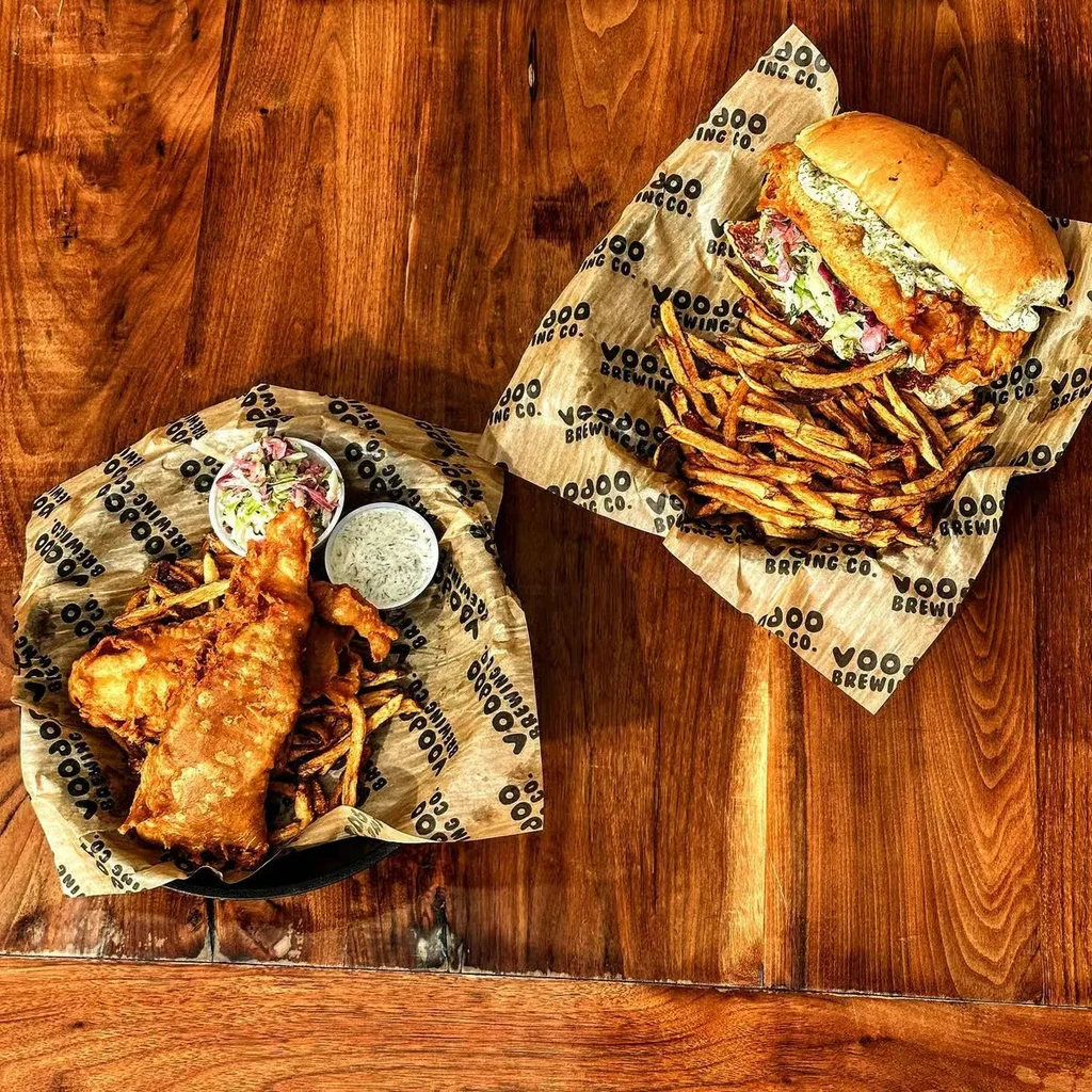 Fish and chips with a fish sandwich on a rustic wooden table.