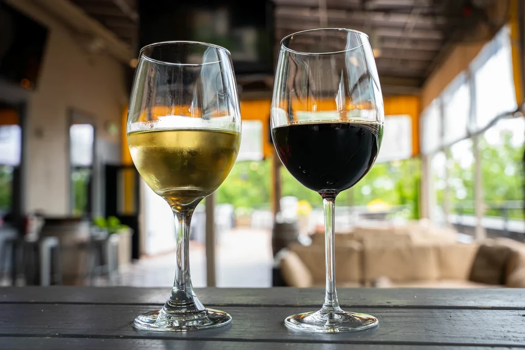 White and red wine glasses on a table in a blurred restaurant.