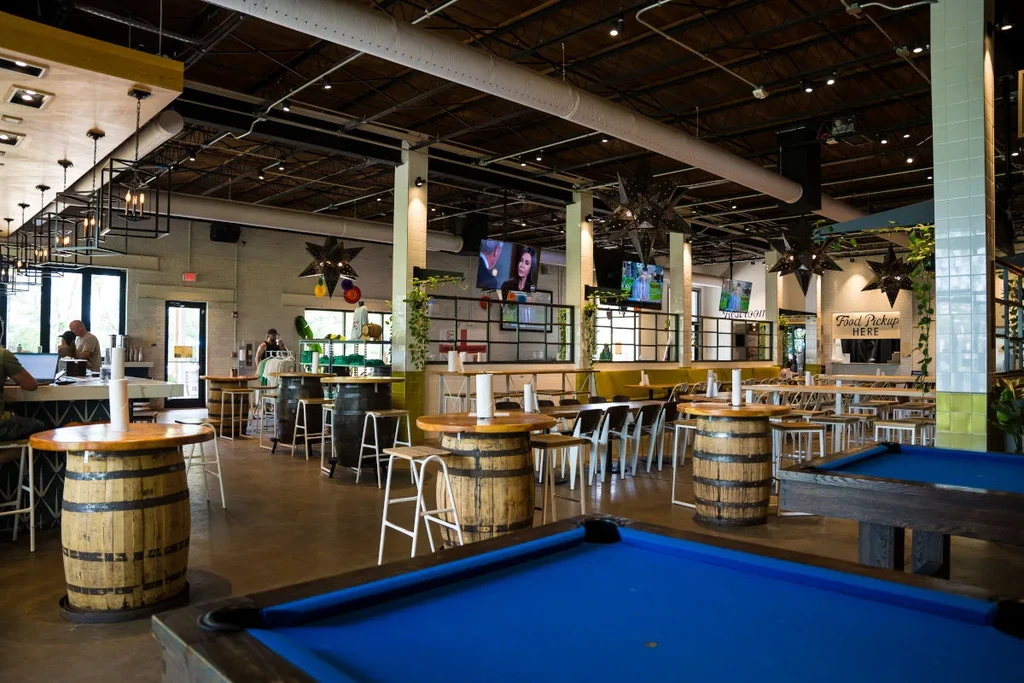 Modern industrial restaurant interior with two pool tables and a bar.