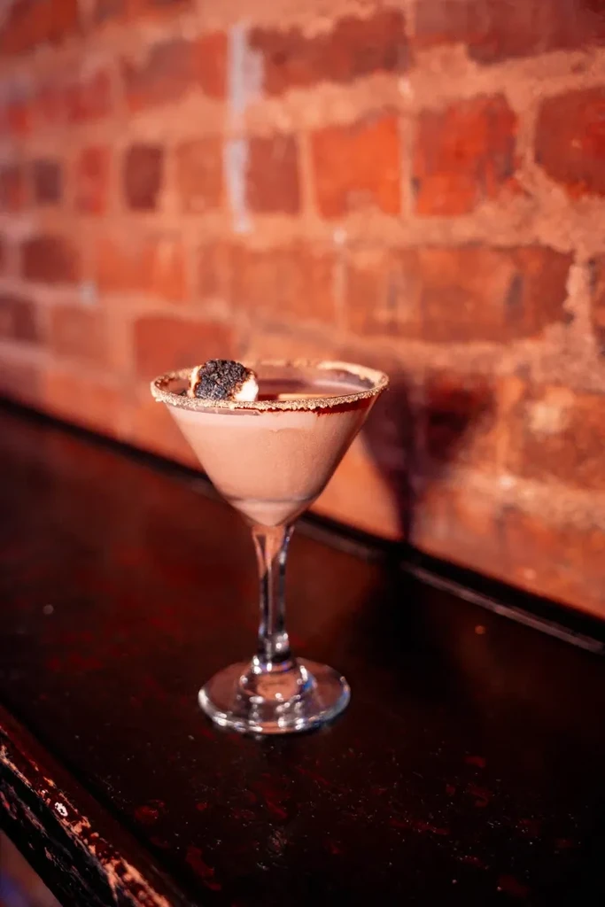 A creamy brown cocktail with a sugared rim and charred marshmallow.