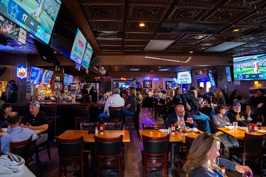 Lively sports bar interior with ornate ceiling, TVs, and many patrons.