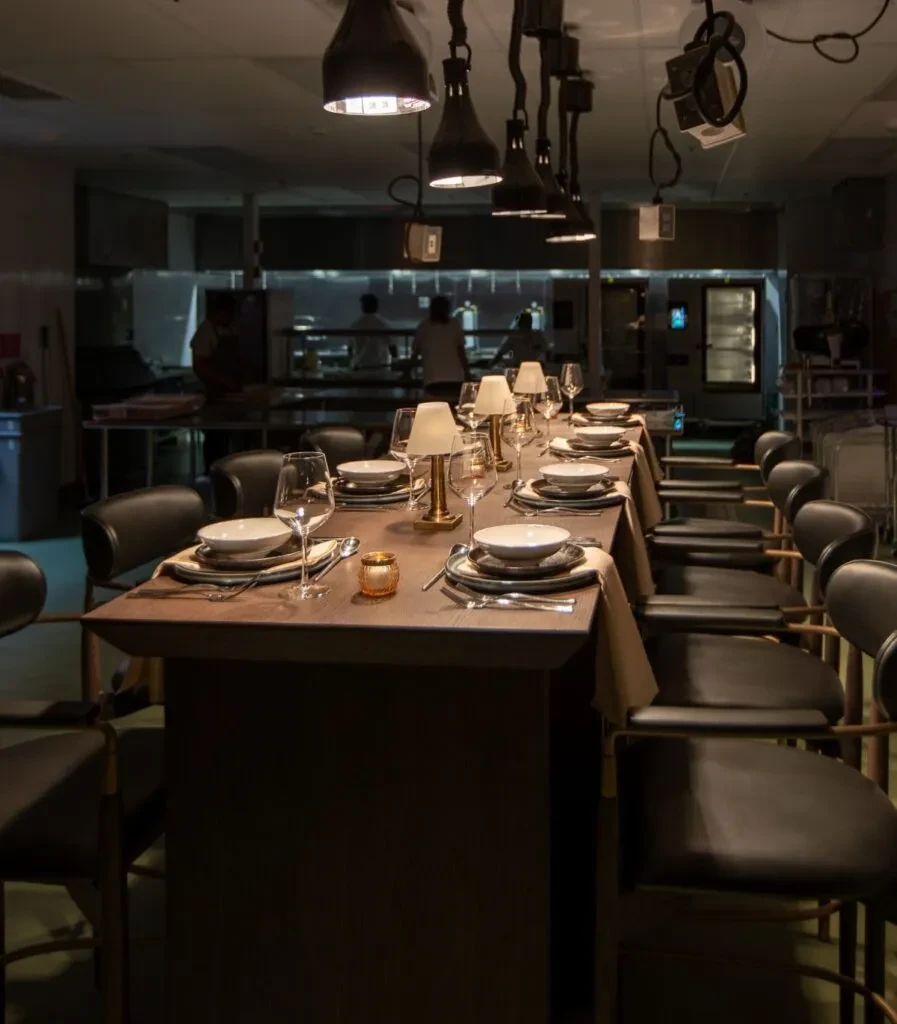Long, set dining table and open kitchen in a modern restaurant.