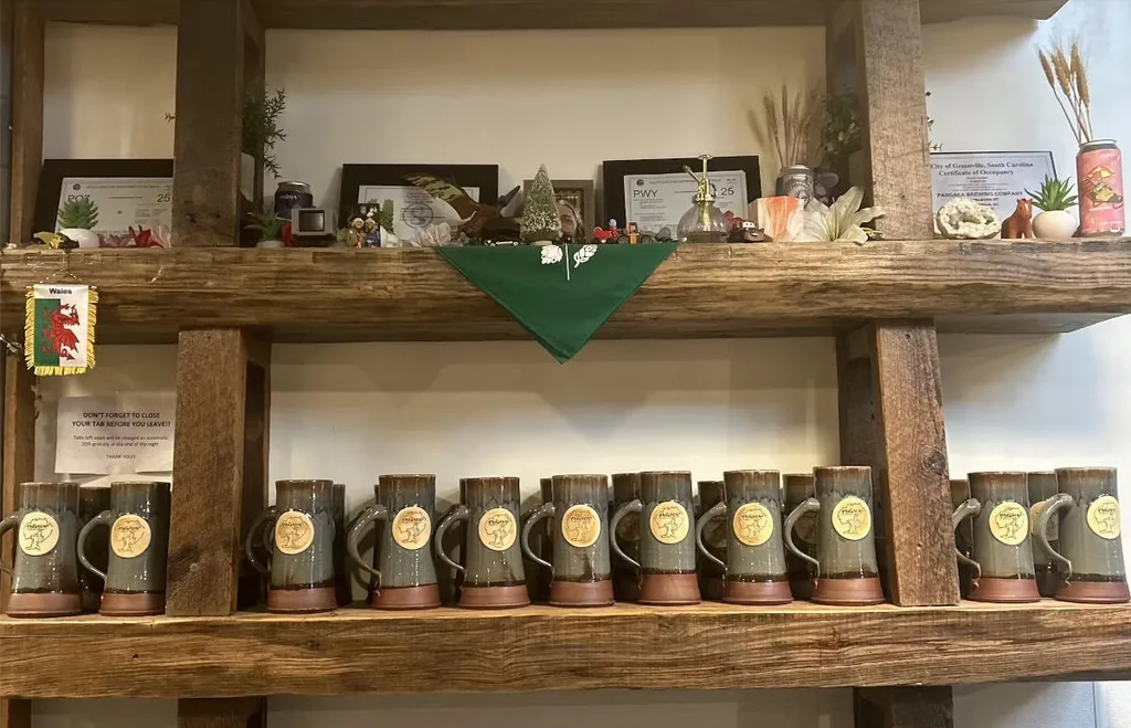 Rustic shelves displaying mugs, certificates, and decor at Pangala Brewing.