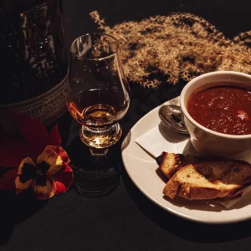 Close-up of Bulleit whiskey, chili, toast, and a pansy flower.