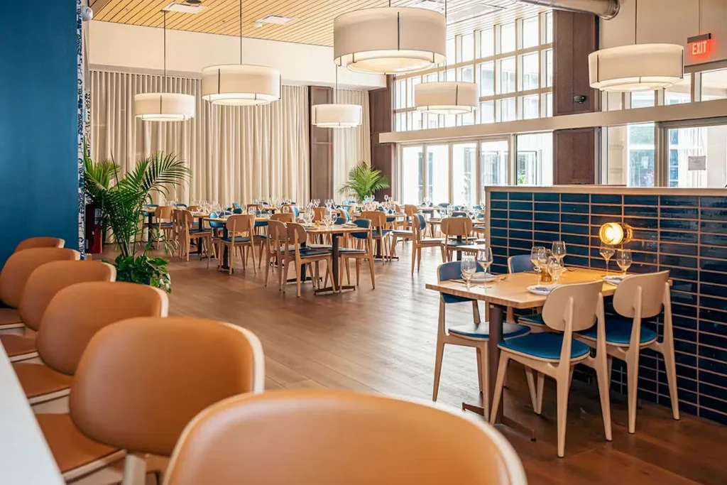 Bright, modern restaurant interior with wooden tables and blue chairs.