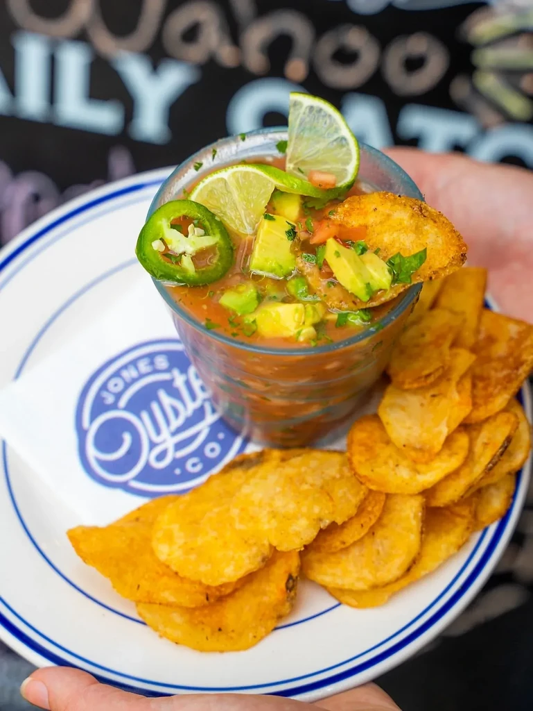 Close-up of seafood ceviche in a glass with avocado, lime, and chips.