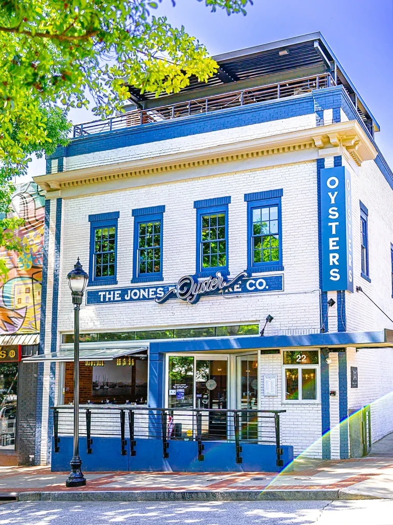White brick restaurant The Jones Oyster Co. with blue trim and rooftop.