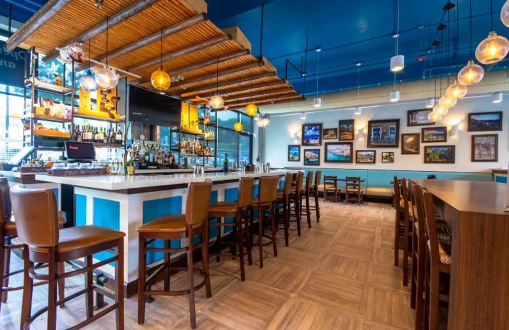 Modern restaurant interior with a vibrant blue bar and varied seating.