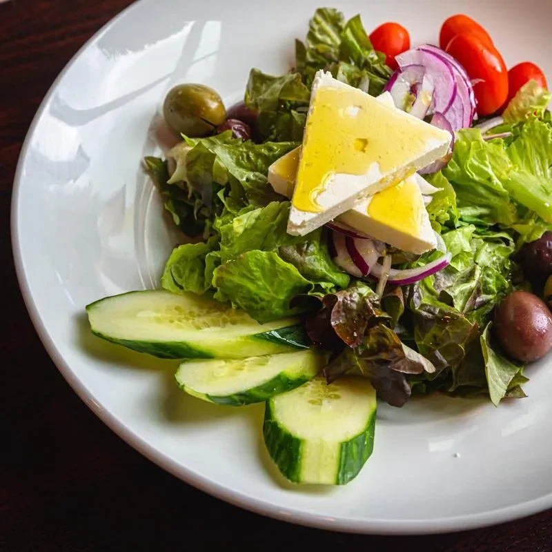 Fresh Greek salad with feta, lettuce, tomatoes, olives, and cucumber.
