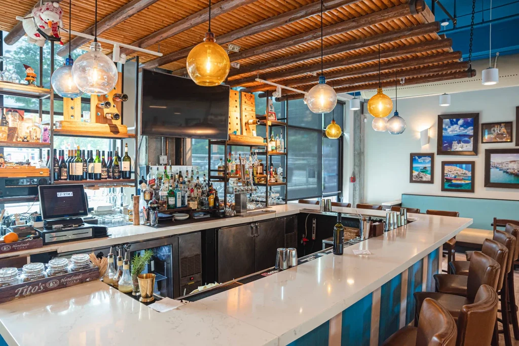 Modern, well-stocked bar area with striped counter, warm lighting, and seating.