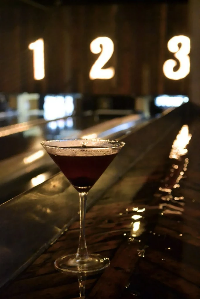 Martini glass with dark cocktail, condensation, glowing numbers 1, 2, 3.