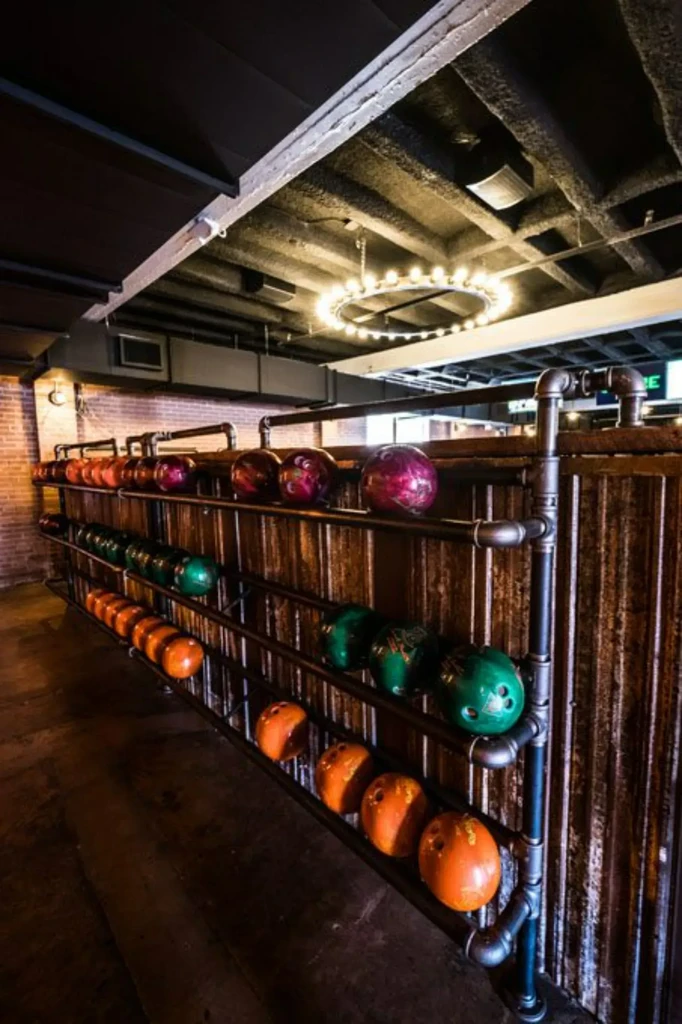 Industrial bowling alley with colorful balls on a dark pipe rack.