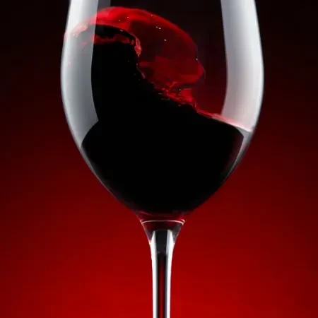 Red wine splashing inside a clear wine glass, dark background.