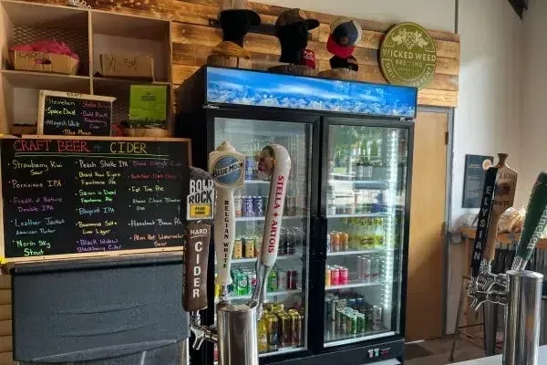 Rustic bar counter displaying craft beer taps and beverage coolers.