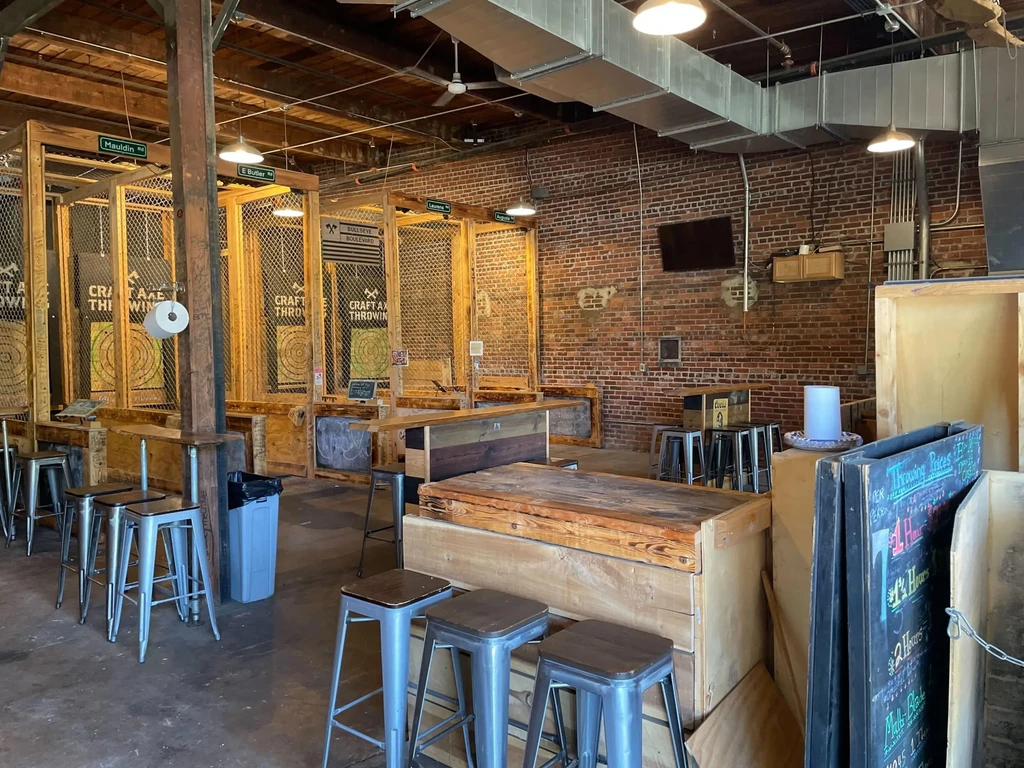Empty rustic industrial axe-throwing venue with lanes and brick walls.