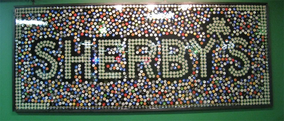 Colorful bottle cap mosaic sign spelling "SHERBY'S" on a green wall.