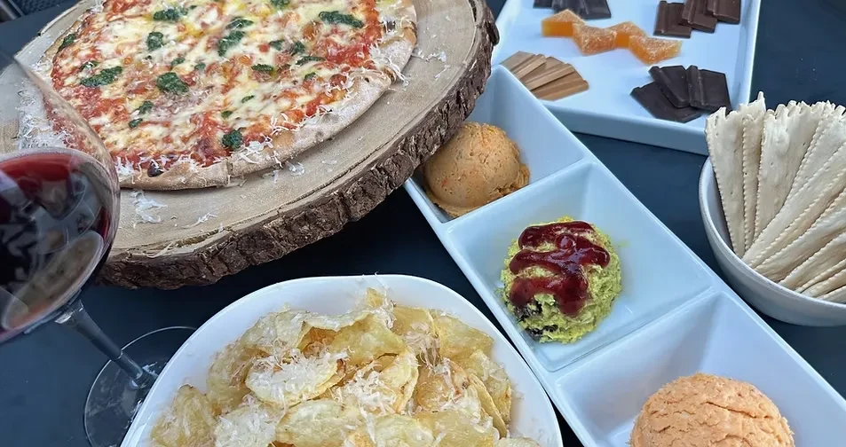 Overhead view: Rustic pizza, chips, dips, crackers, and dessert.