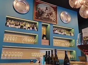 Teal-walled wine bar with backlit shelves of bottles and glasses.