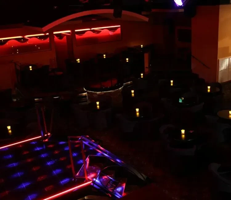 Dimly lit nightclub with red, blue lights and a laser dance floor.