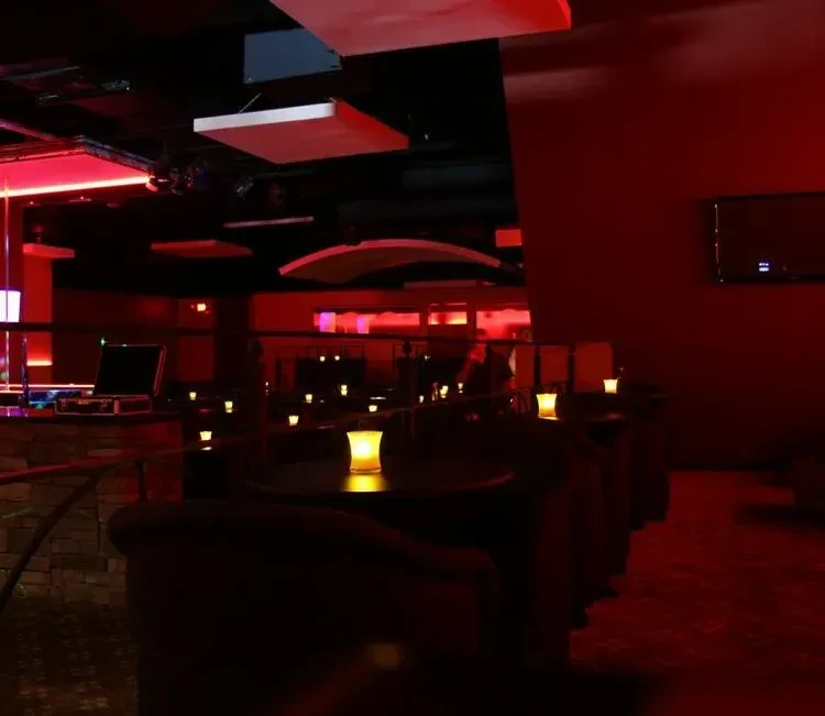 Dimly lit red lounge with yellow table lights and dark seating.