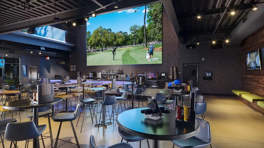 Modern industrial restaurant interior with a large screen showing golf.