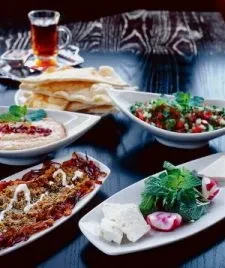 Middle Eastern appetizers: flatbread, salad, cheese, stew, and tea.