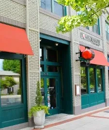 Brick building exterior, green doors, red awnings, and red spherical light.