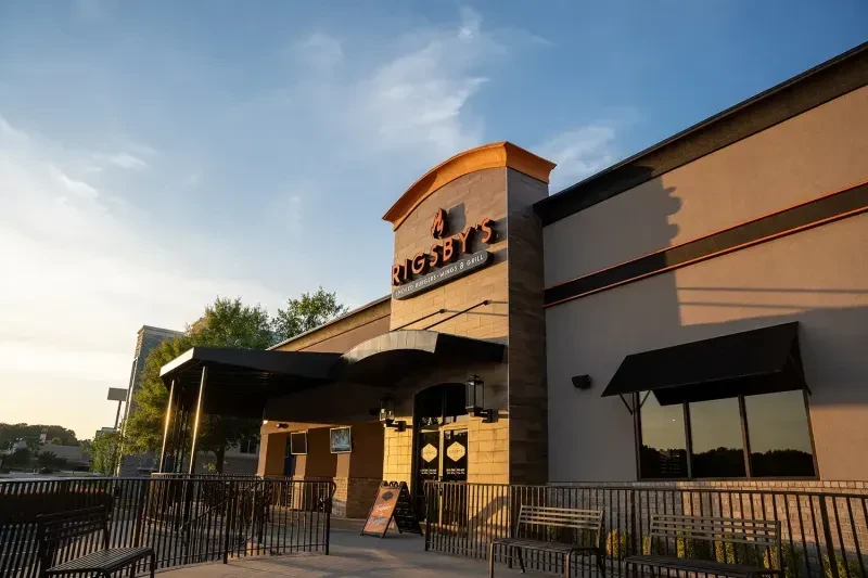 RIGSBY'S modern restaurant exterior with patio seating under golden light.