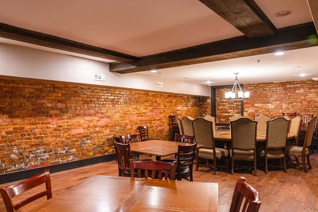 Empty restaurant interior featuring exposed brick walls and wooden dining furniture.