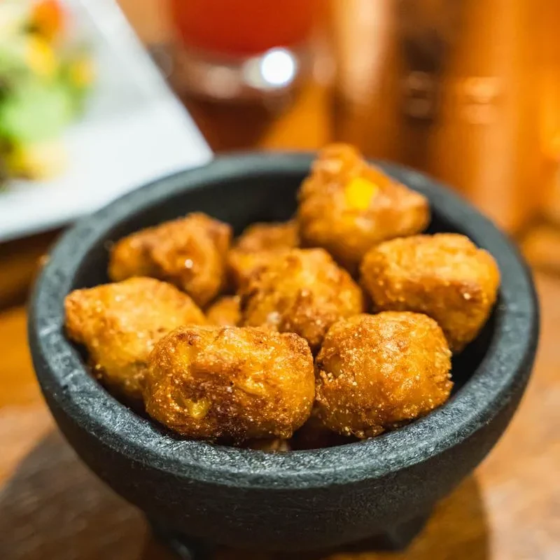 Dark stone bowl filled with golden-brown crispy fried snacks.