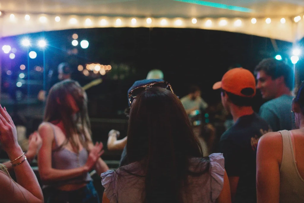 People enjoy a lively evening event with live music under string lights.