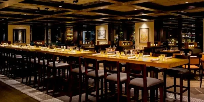 Empty upscale restaurant interior with long communal high-top table, set.