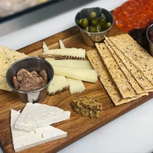 Rustic charcuterie board with cheeses, crackers, pâté, pickles, and spreads.