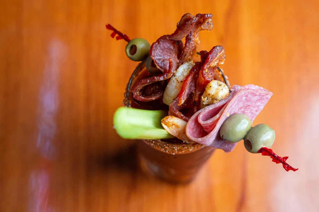Heavily garnished Bloody Mary with bacon, shrimp, olives, and celery.