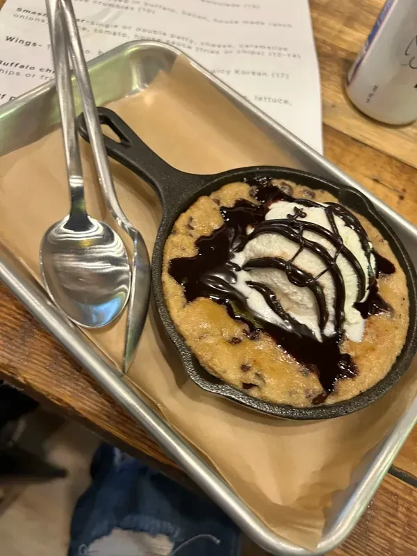 Warm chocolate chip cookie skillet with ice cream and chocolate syrup.
