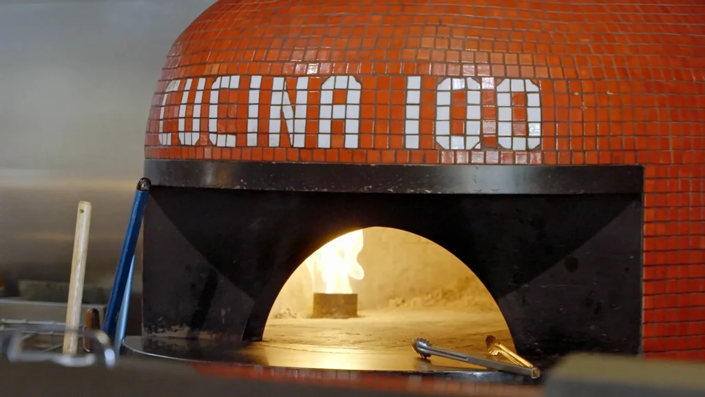Mosaic pizza oven "CUCINA 100" with glowing flames and kitchen tools.