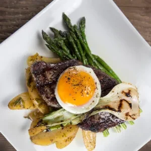 Gourmet steak, sunny-side-up egg, asparagus, and roasted potatoes.