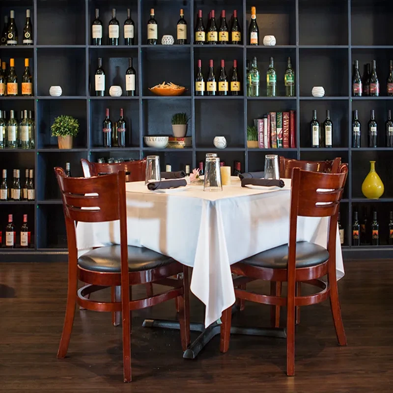 Empty restaurant table set before a large, dark wine display.