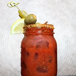 Bloody Mary in mason jar, spiced rim, olive, pickle, lemon.