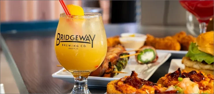 Bridgeway Brewing Co. drink, orange slice, and various appetizers.