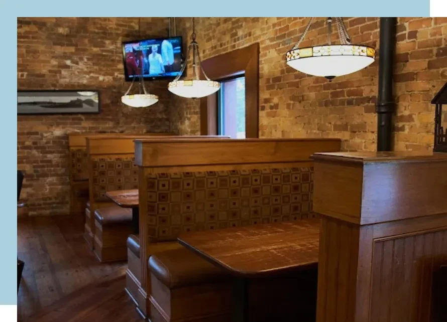 Restaurant interior with brick walls, wooden booths, and Tiffany lights.