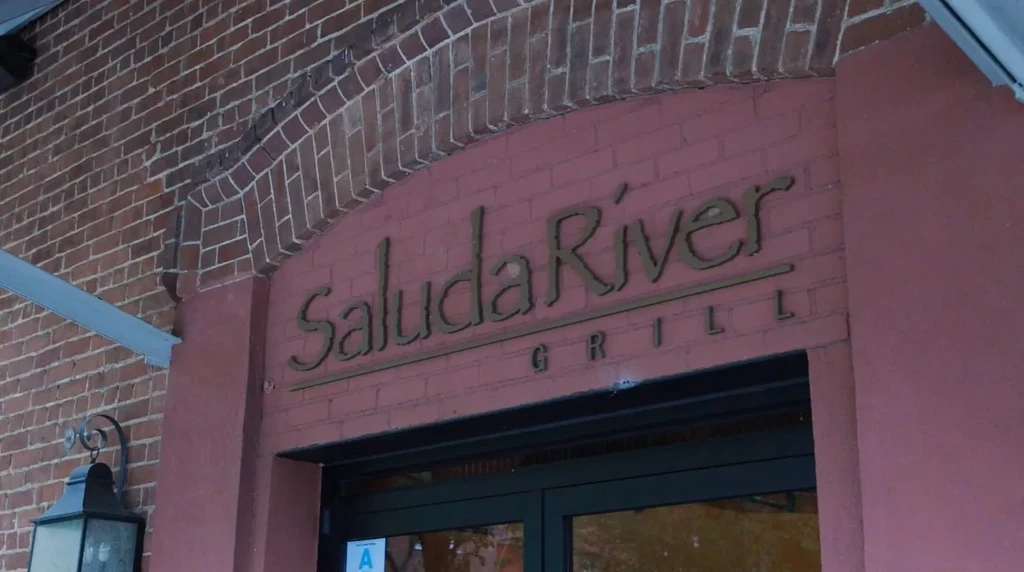 Exterior of Saluda River GRILL entrance with brick archway and gold signage.
