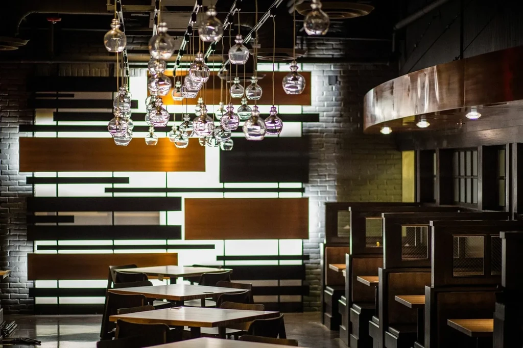 Industrial-chic restaurant interior with spherical lights, booths, and wood paneling.