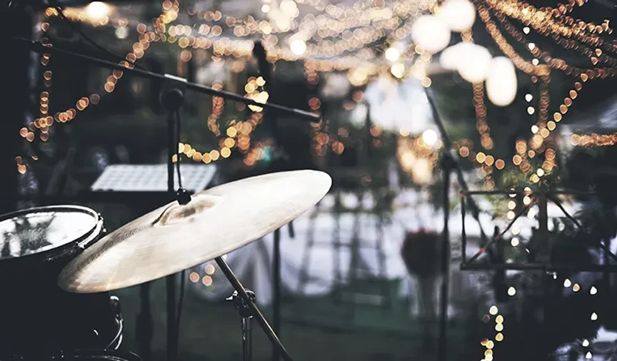 Close-up of a drum cymbal with warm bokeh lights in background.
